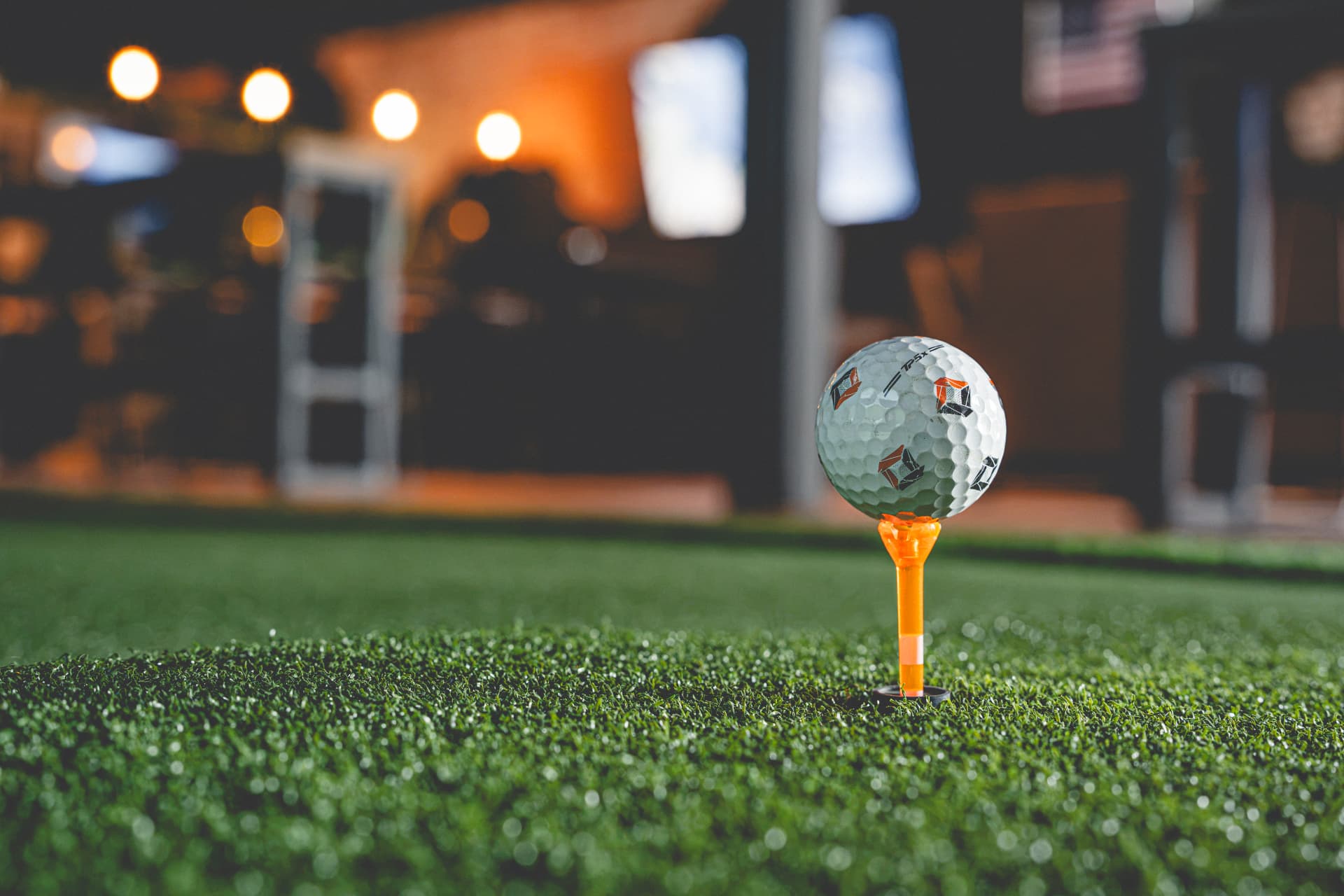 Golf ball on an orange tee on the turf at Off Course