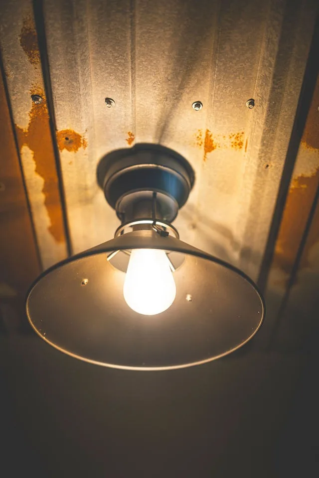 An industrial pendant light under a metal ceiling