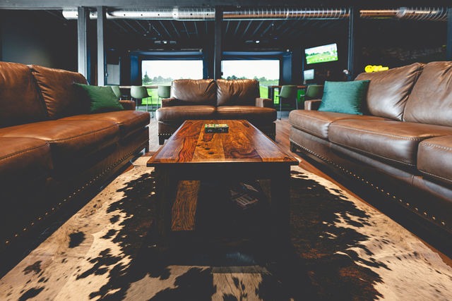 Leather couches around a wood coffee table on a cowhide rug, looking out to the bays