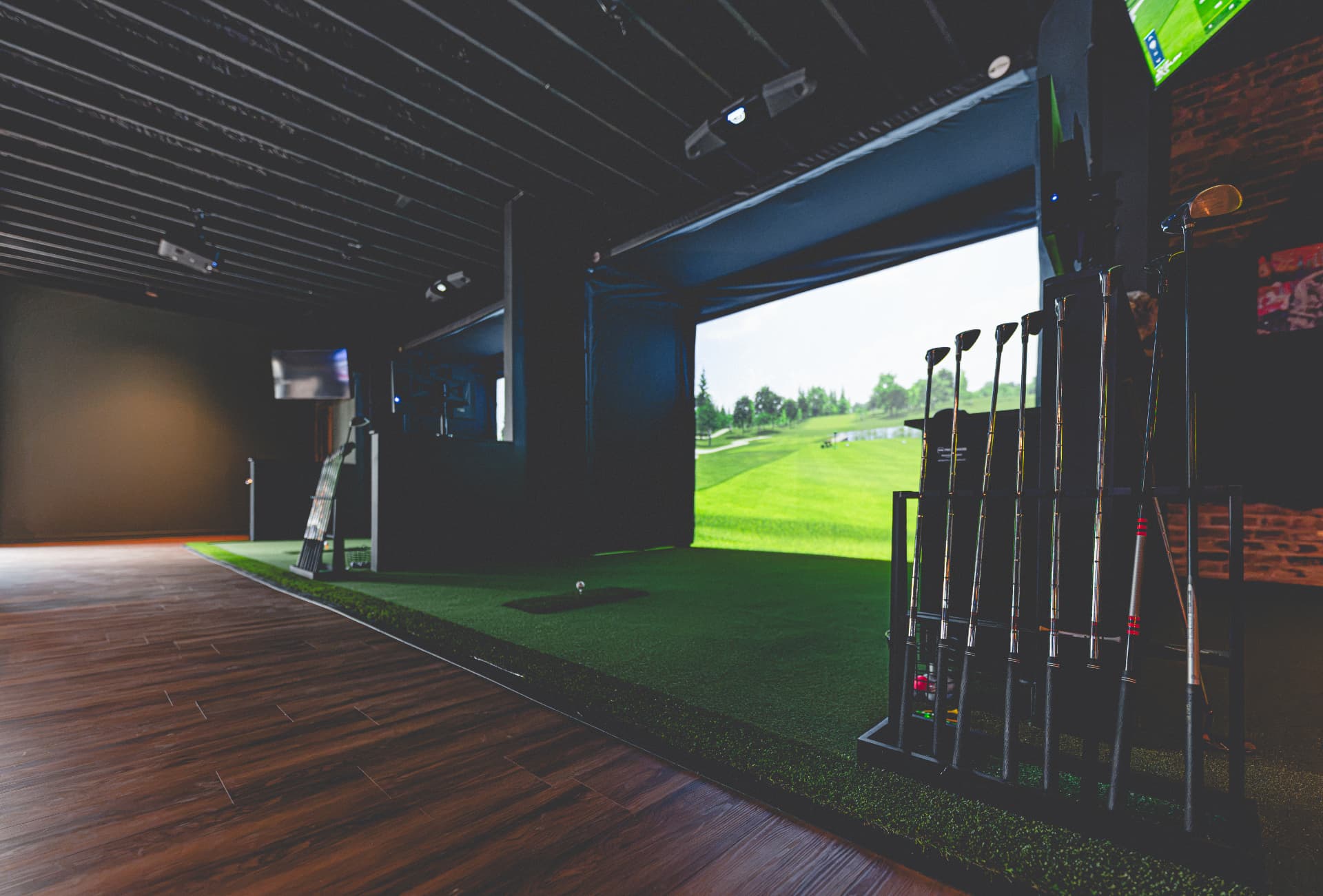 Off Course premium indoor golf simulator bay with clubs and large screen