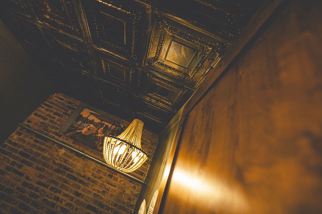 A beaded chandelier against brick under the tin ceiling