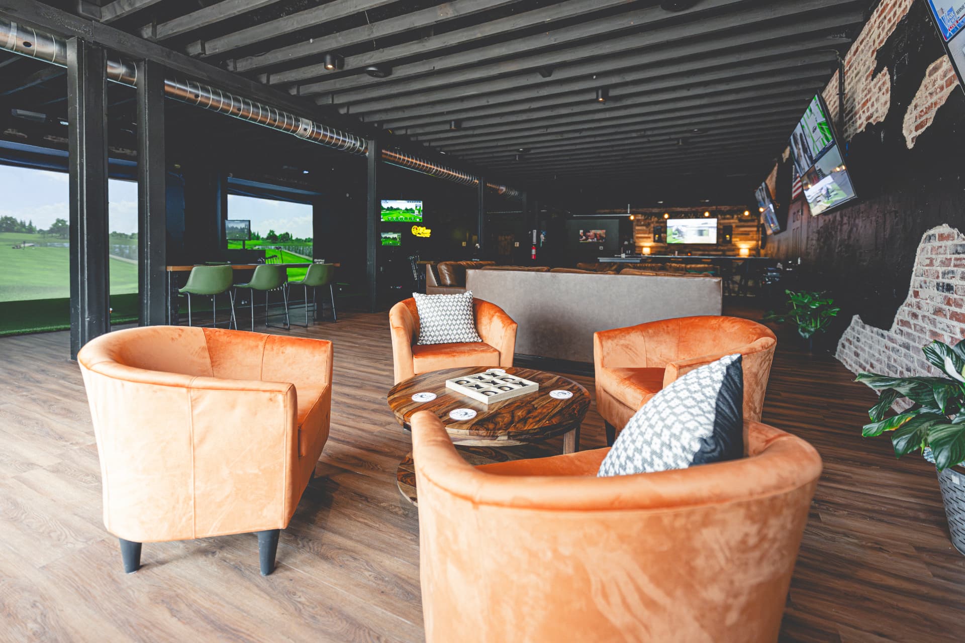 Off Course lounge with plush seating, golf simulators and warm club lighting
