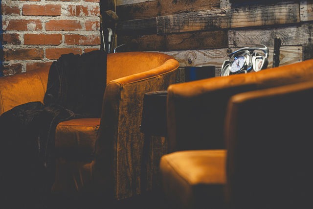 An orange velvet chair with a jacket draped over it