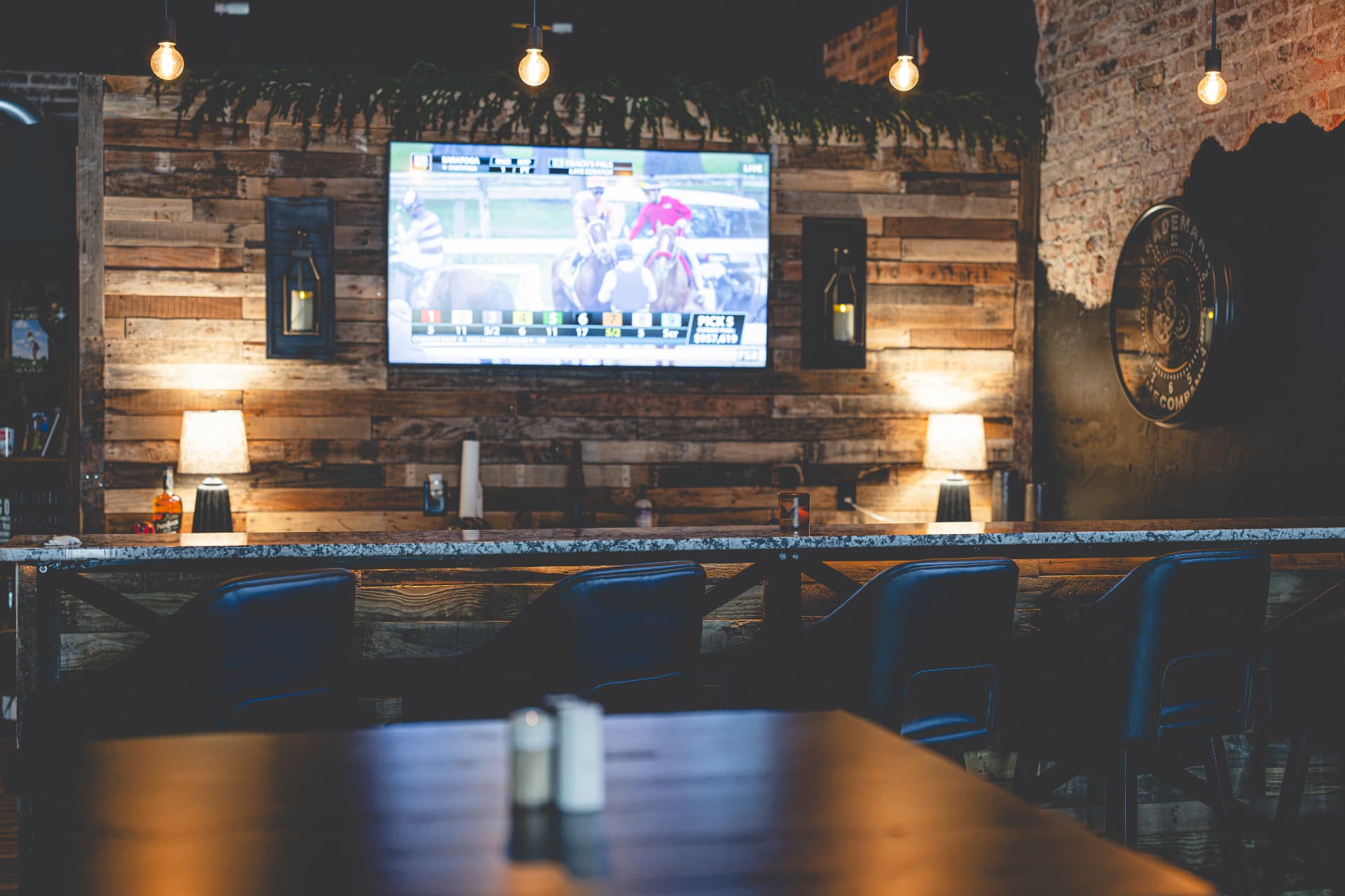 Bar seating with reclaimed wood wall and TV at Off Course