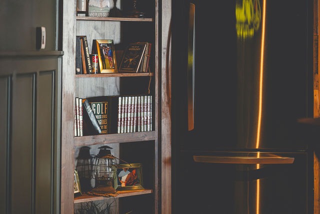 A wood bookshelf stocked with golf books and a lantern